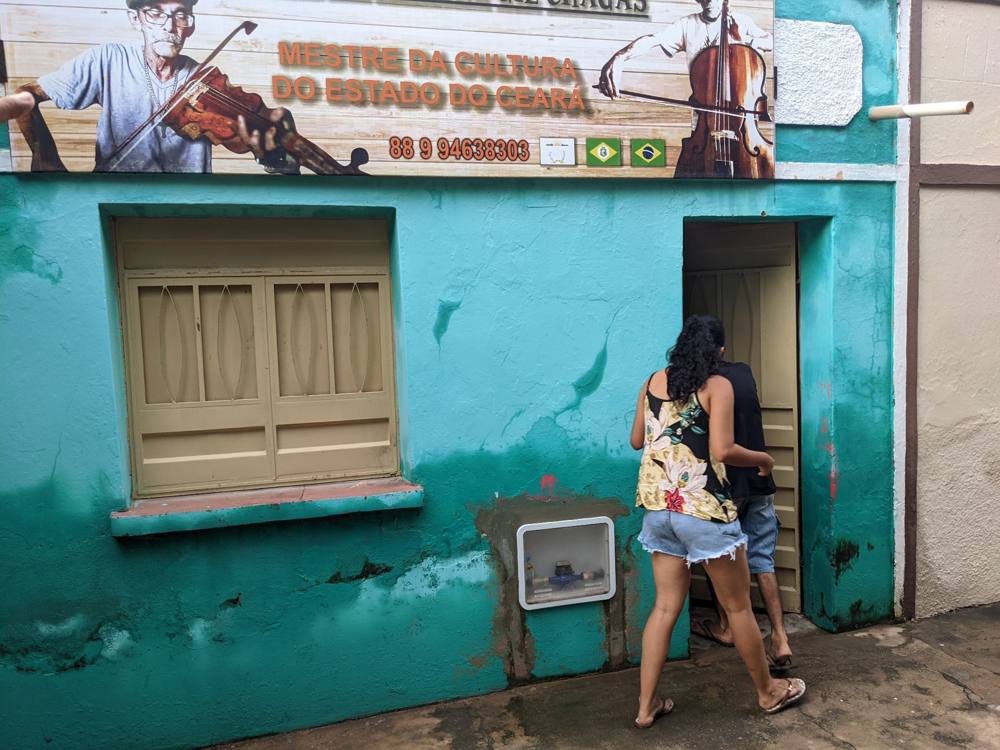 A turquoise house in Ceará under a banner reading Mestre da Cultura do Estado do Ceará