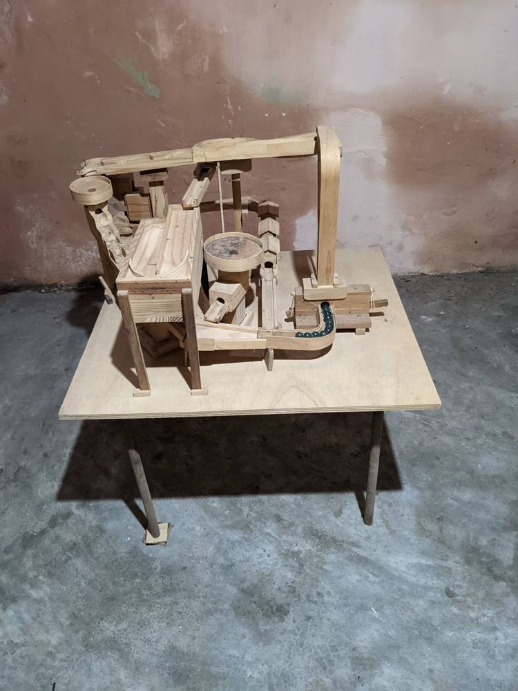 A hand-built wooden marble machine on a plywood table
