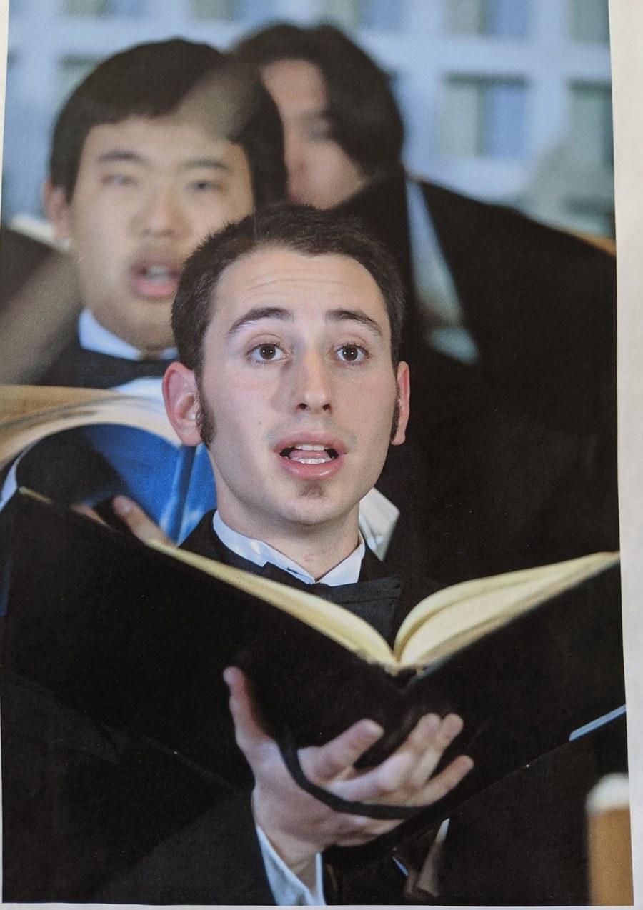 Michael singing in the Bates College choir, music folder in hand
