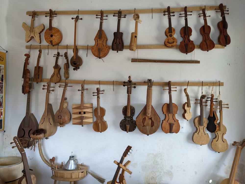 A home wall covered with rabecas of every shape: butterfly, round, gourd, and fiddle forms