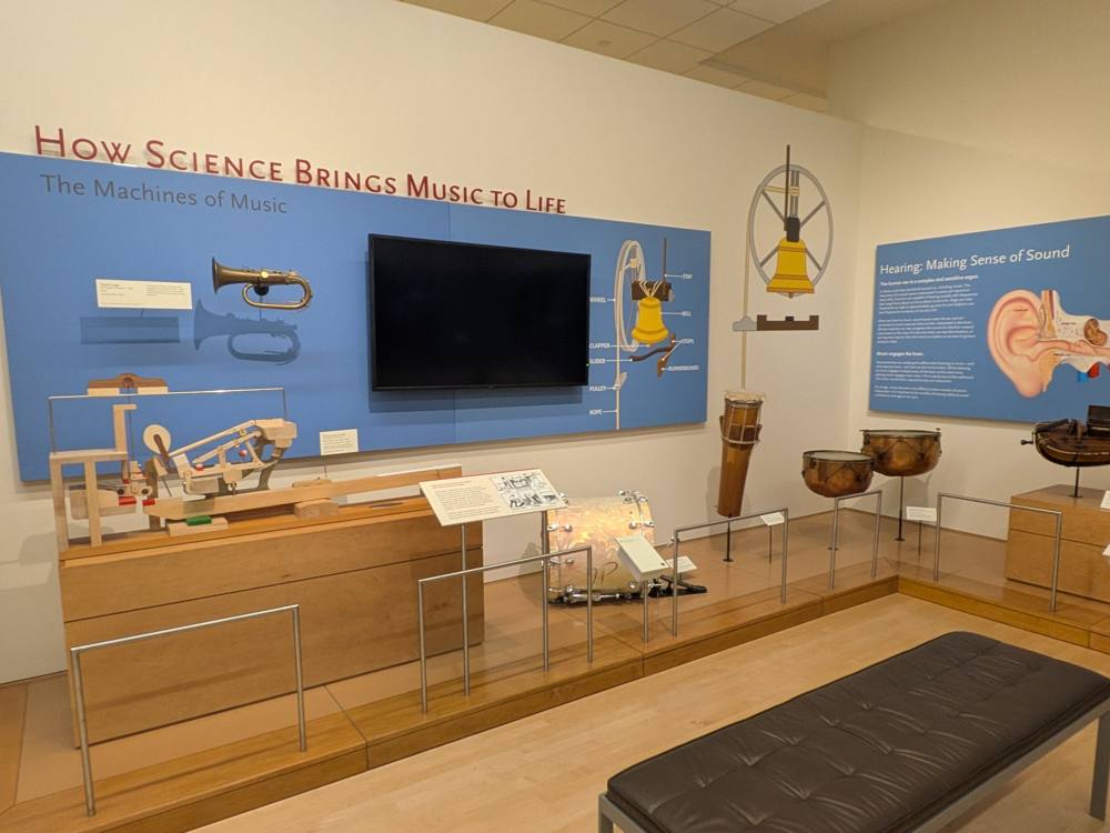 The Machines of Music wall: an opened piano-action model, drums, a bell-ringing diagram, and the Hearing panel