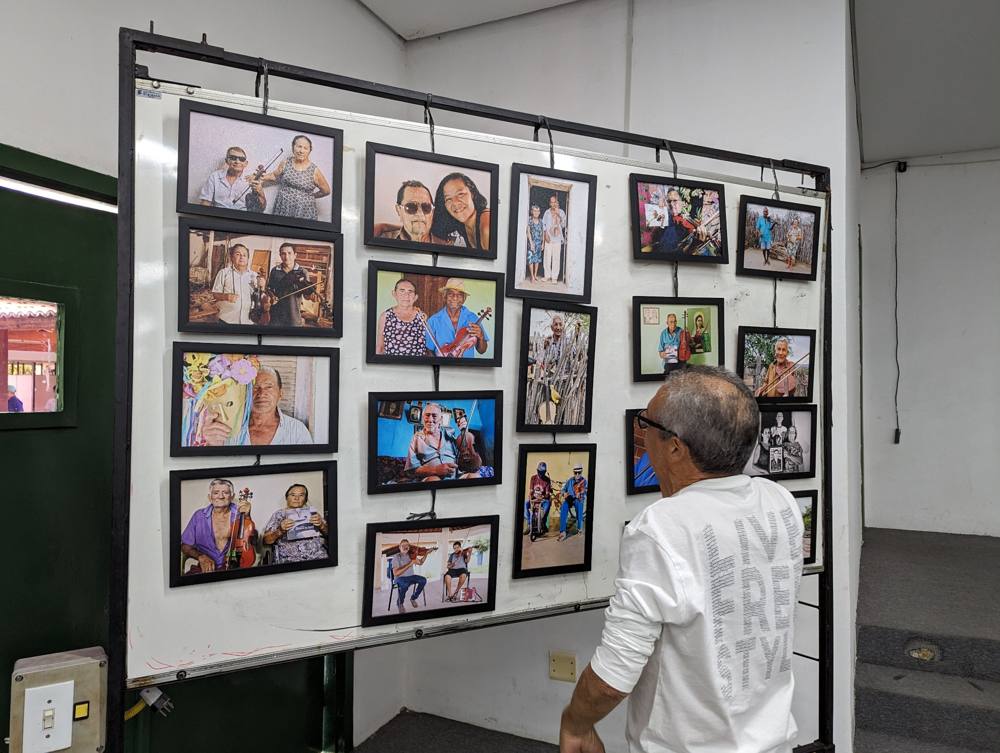 A visitor looking at a wall of framed portraits of rabequeiros at the Federal Institute in Tauá