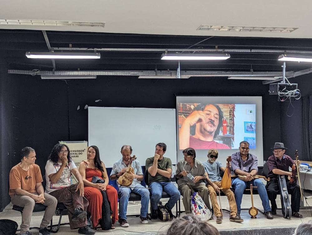 Freitas speaking on a stage at the Federal University of Cariri, with a video of himself on the screen