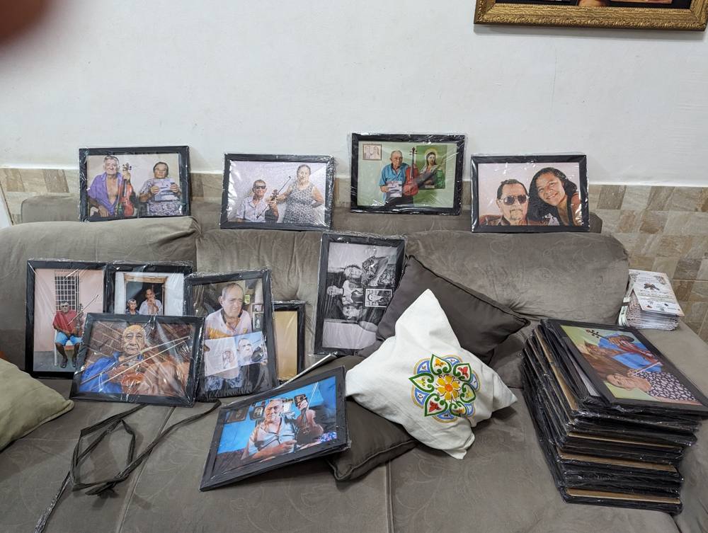 Framed portraits of rabequeiros arranged on a couch, wrapped and ready